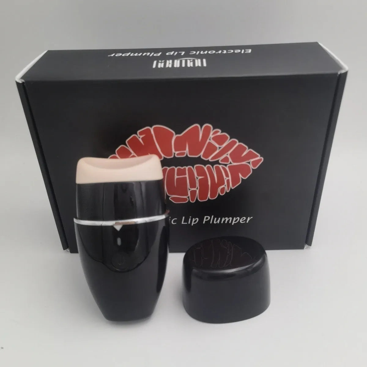 Black and white electric lip plumper device with USB charging cable on a plain background.