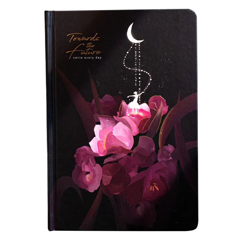 A5 notebook with luminous cover in deep blue, open to show lined pages with colour illustrations.