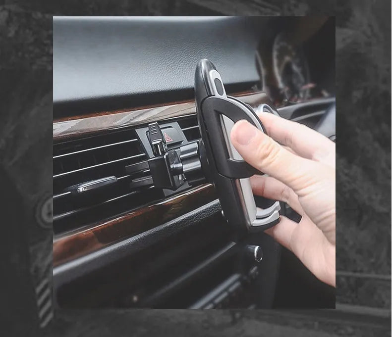 Black plastic car mobile phone holder mounted on air conditioning vent with adjustable arms gripping smartphone