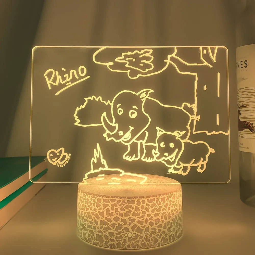 Black 3D LED handwritten acrylic message board with remote control on a desk.