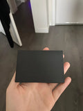 Plain black mailing envelope measuring 9 cm by 6 cm, shown flat with a flap