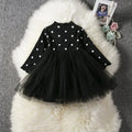 Baby girl in a long sleeve black tutu lace dress for a birthday party or christening