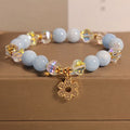 Women's aquamarine crystal bracelet featuring a four-leaf clover charm and pearl decorative elements.