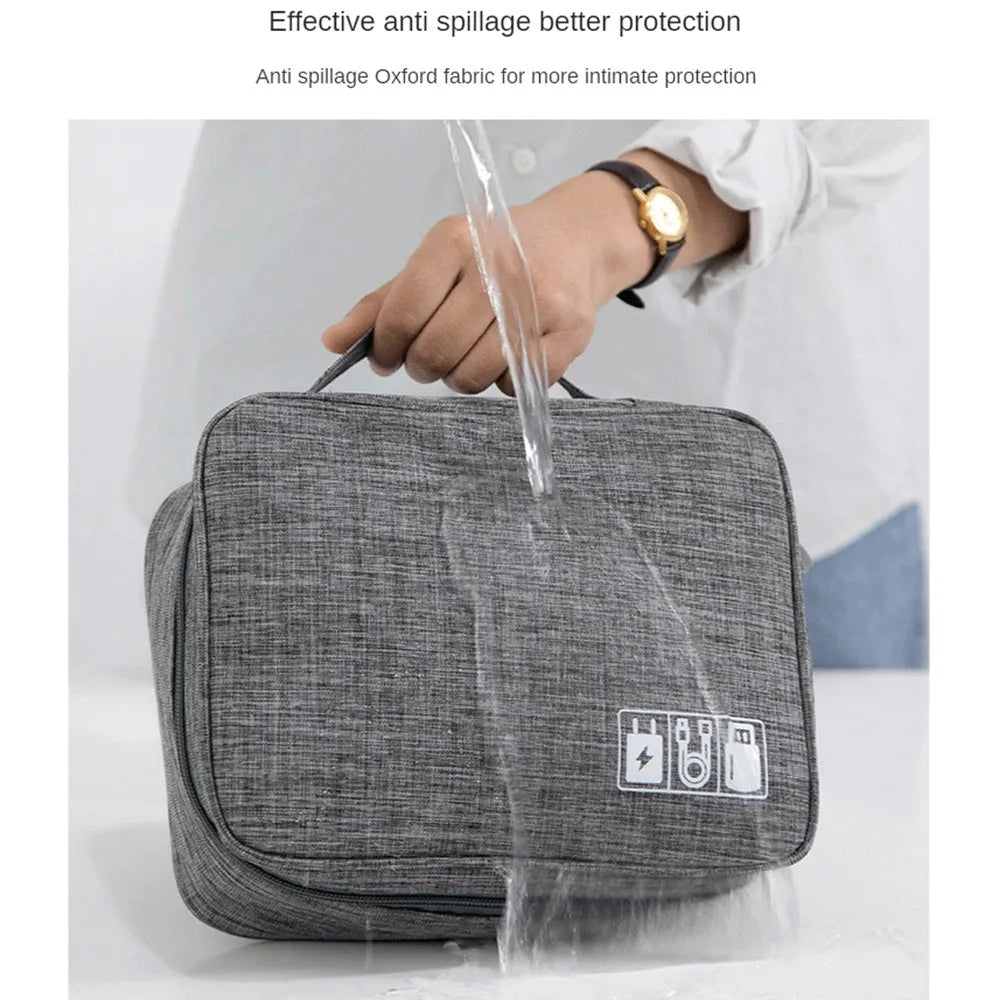 Black travel cable organiser bag open, showing mesh pockets, elastic loops, and removable padded dividers inside.