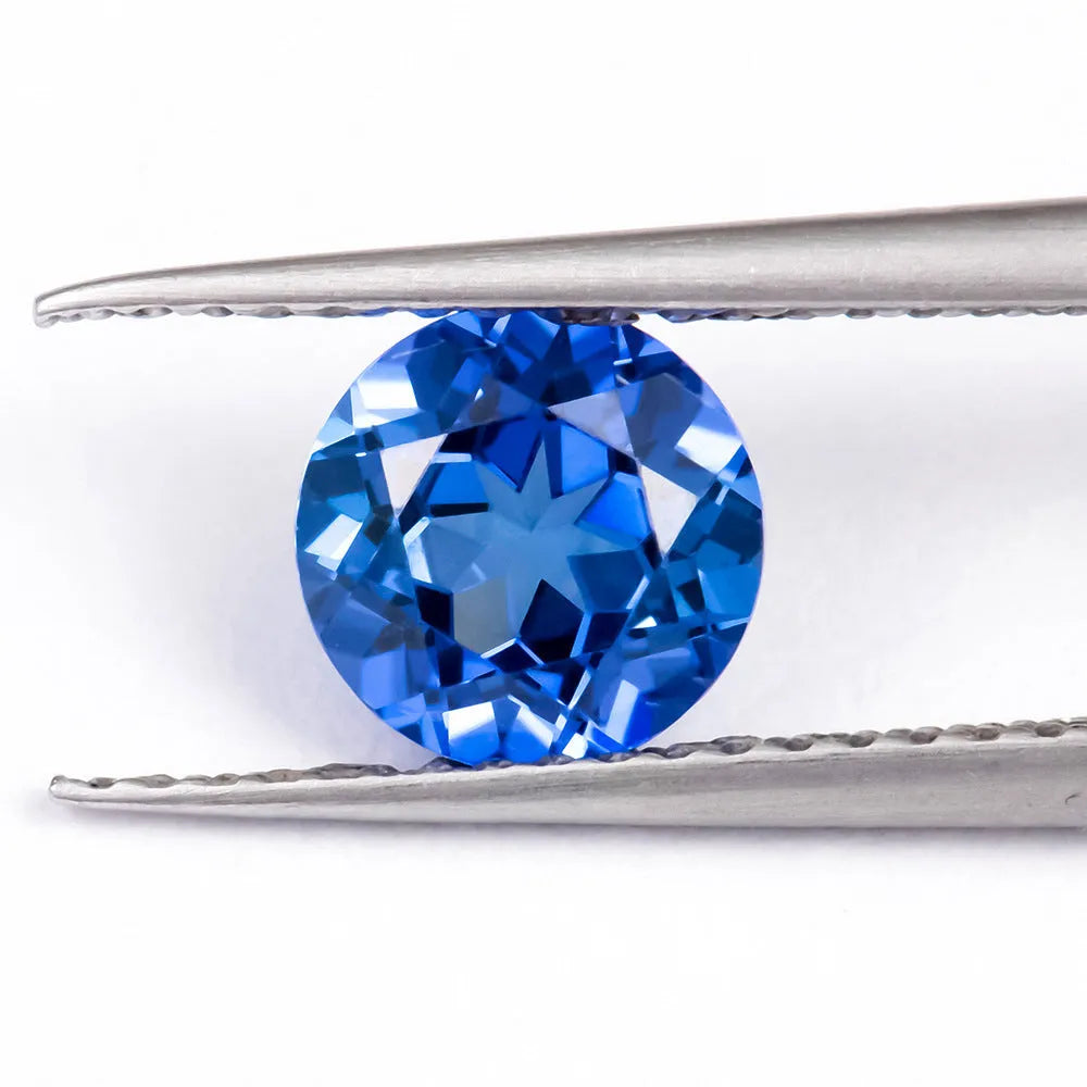 Royal blue loose gemstone in heart, round, and pear shapes on a white background.