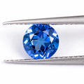 Royal blue loose gemstone in heart, round, and pear shapes on a white background.