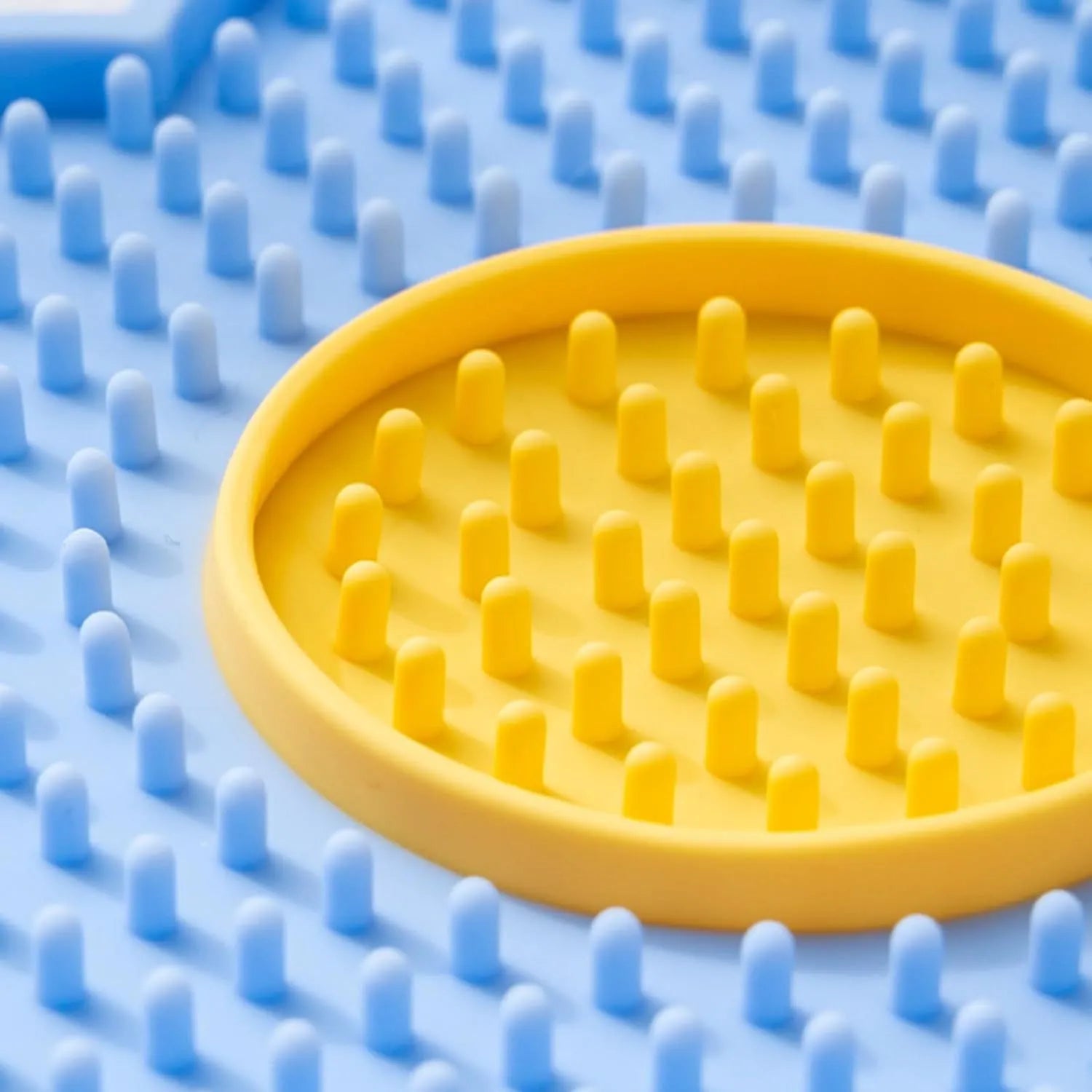 A blue flower-shaped silicone lick mat for pets with four white suction cups on the underside.