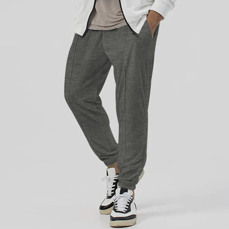 Men's grey loose tapered track sweatpants with elastic waist and straight leg design.
