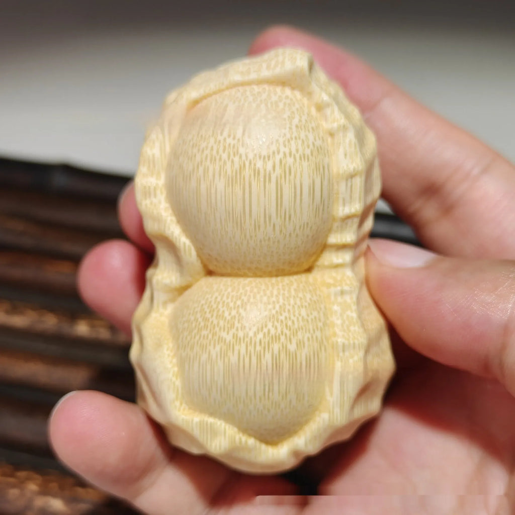 Solid natural bamboo ornament carved into a peanut shape on a plain background.