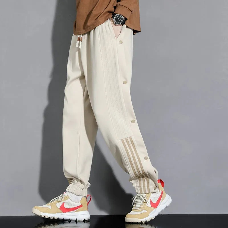Men's black high-waist sweatpants with ankle-tied cuffs and a drawstring waist on a grey background.
