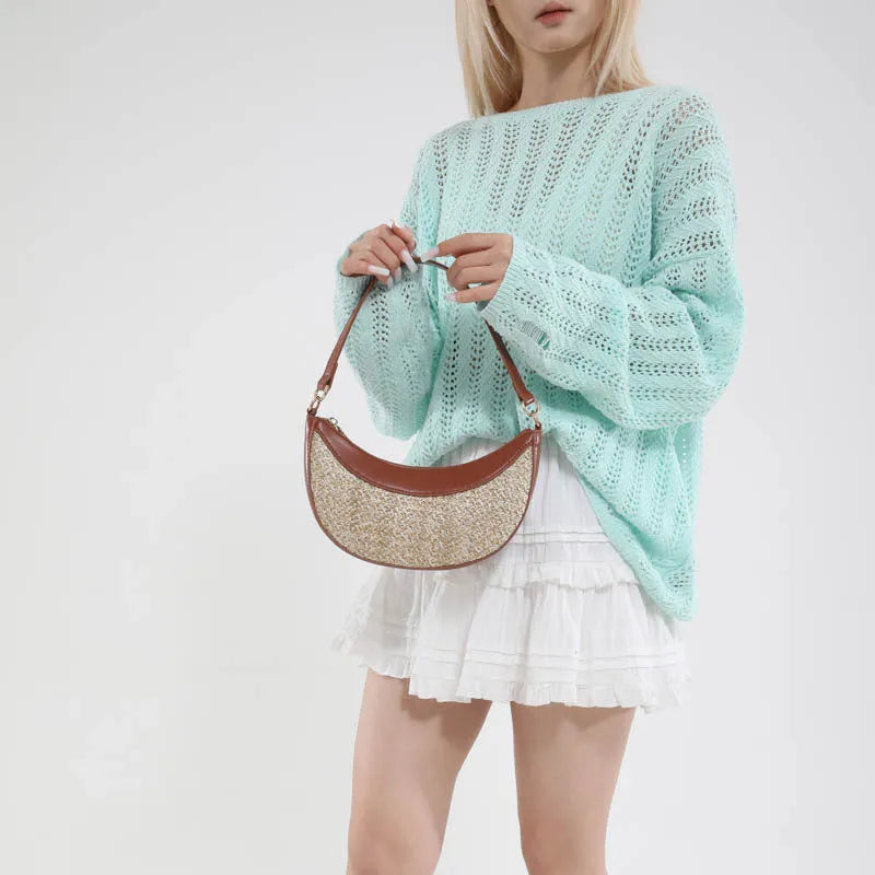 Straw crossbody dumpling bag in a hard suitcase shape with a single shoulder strap.