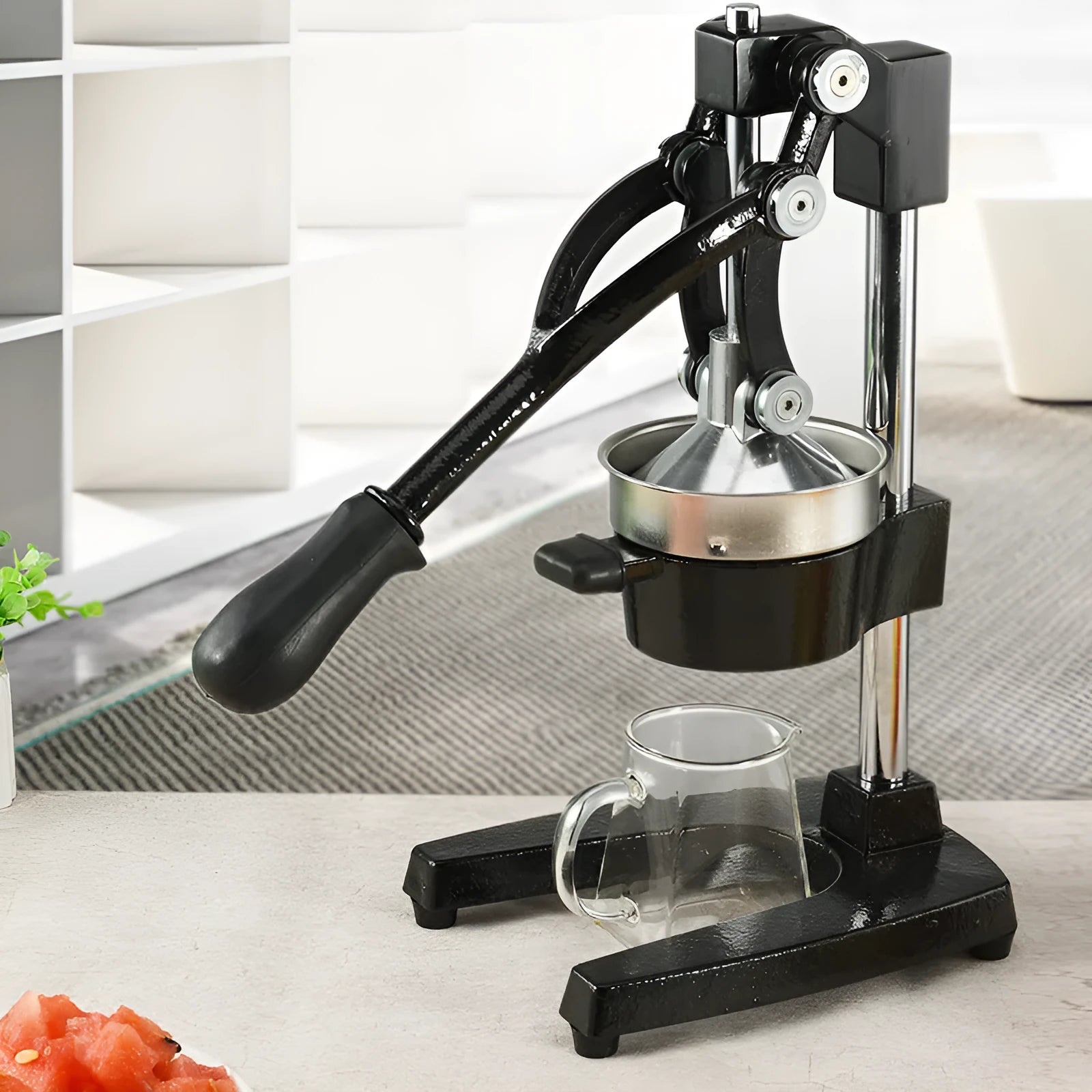 Tall black cast iron manual citrus juicer with stainless steel strainer on a kitchen counter.