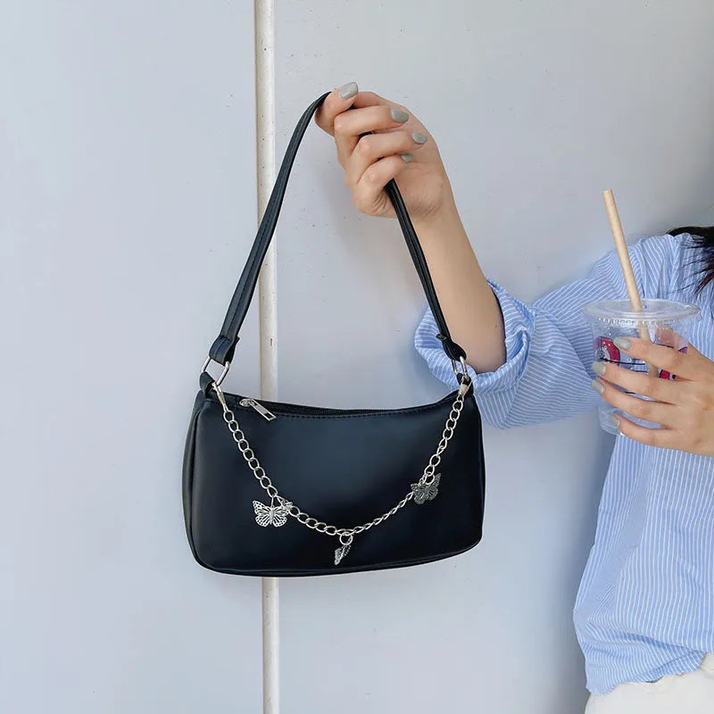 Women's black PU leather crossbody bag with butterfly chain shoulder strap showing internal phone pocket