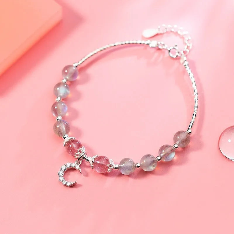 Handmade adjustable bracelet with a natural moonstone and silver crescent moon charm on a wrist.