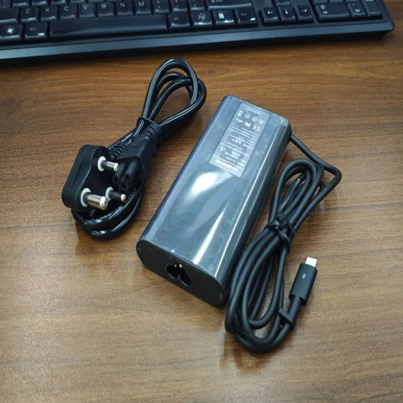Black 65W USB-C laptop power adapter with a set of international plug cords for UK, US, EU, AU and SA sockets.