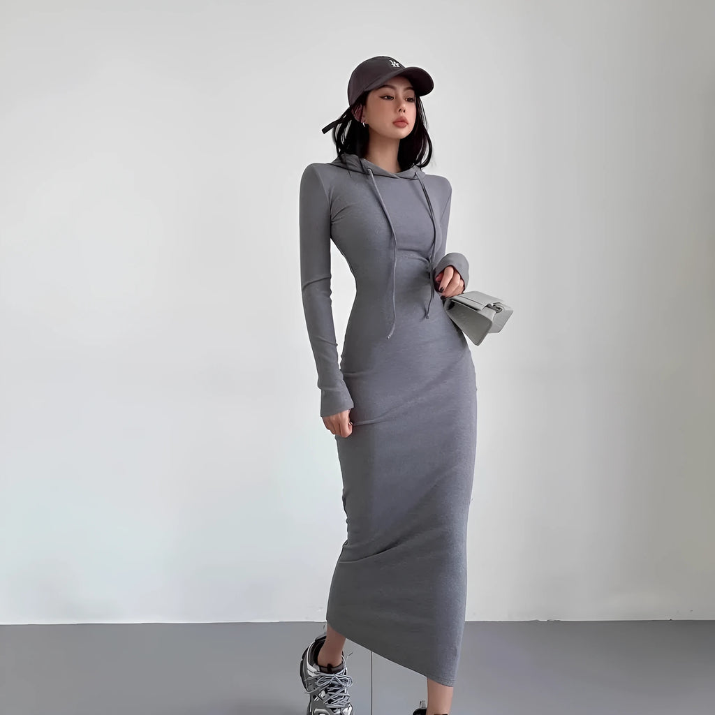A woman wearing a light grey hooded sheath dress with long sleeves, showcasing the high waist and over-the-knee length.
