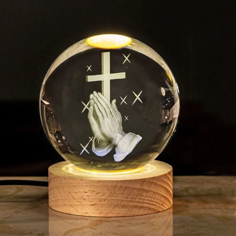 White crystal ball ornament on wood base with warm light and religious symbols