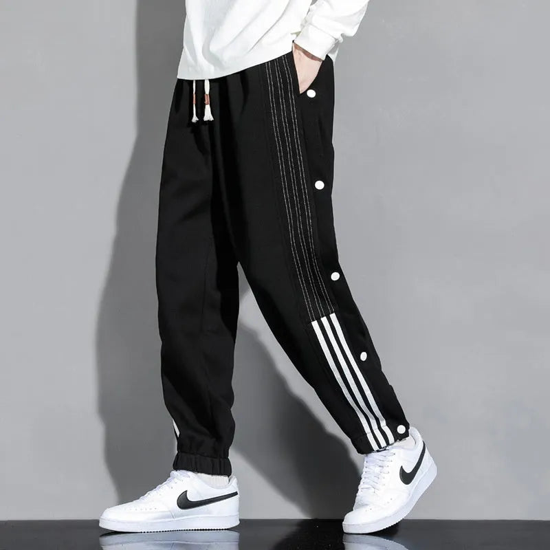 Men's black high-waist sweatpants with ankle-tied cuffs and a drawstring waist on a grey background.