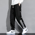 Men's black high-waist sweatpants with ankle-tied cuffs and a drawstring waist on a grey background.