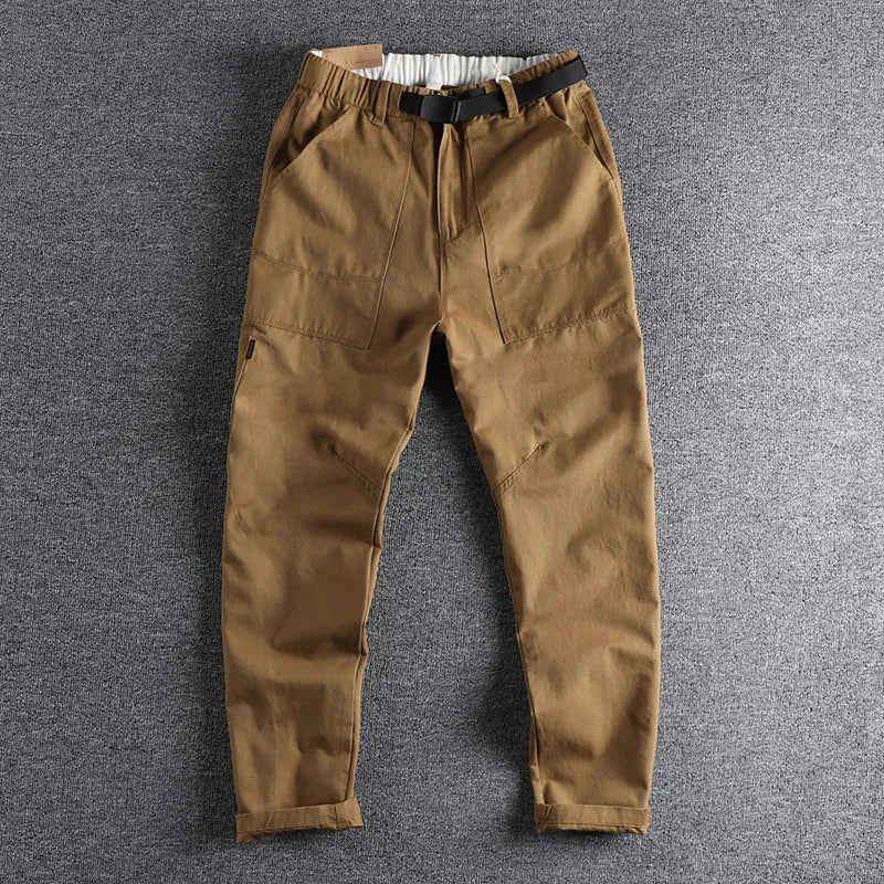 Men's khaki cotton work trousers with a black buckle belt and zip fly closure.