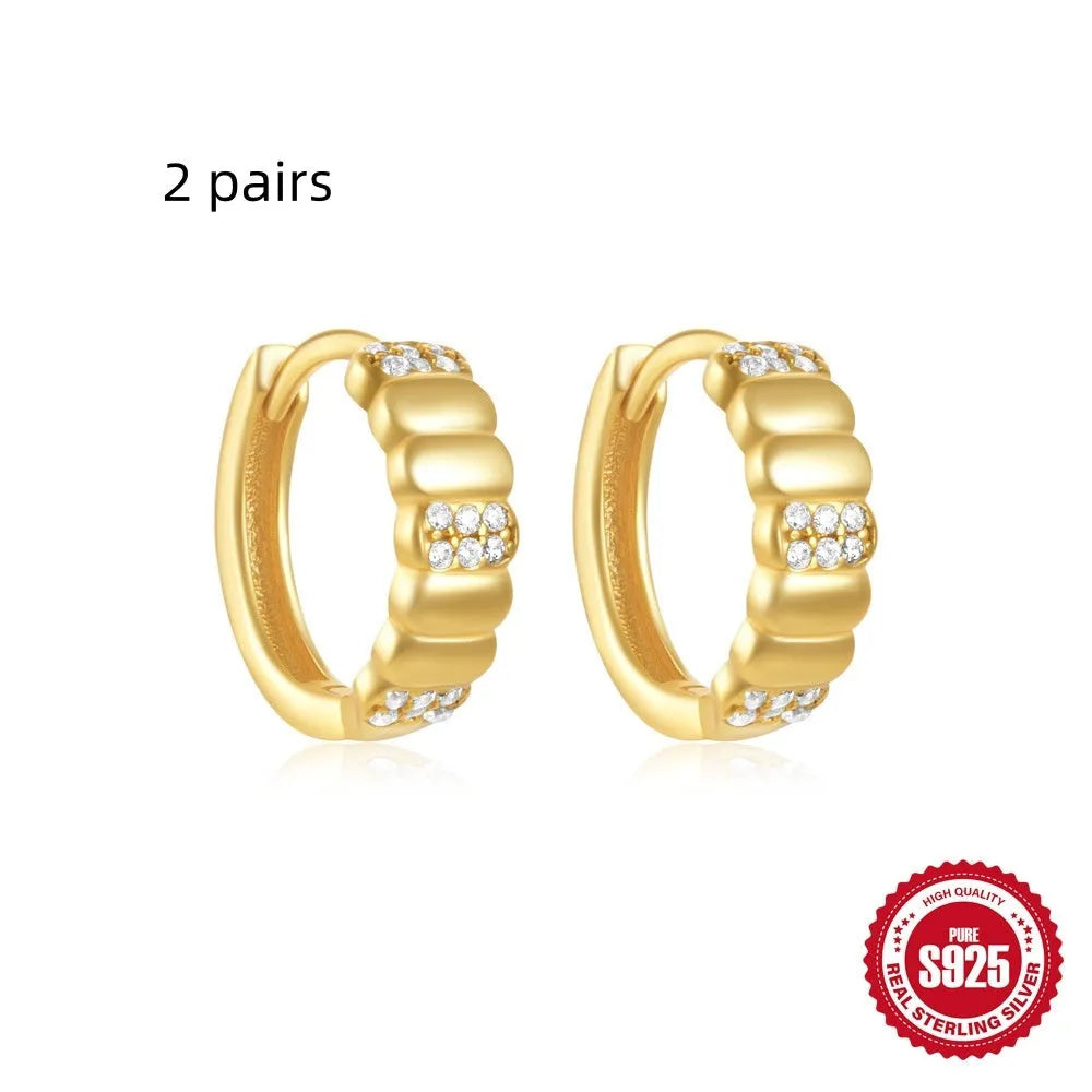 A pair of small, round, geometric stud earrings made of sterling silver with an electroplated finish.