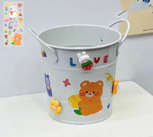 Round metal pen holder in a choice of colours including pink, green, red, white and yellow on a desk.