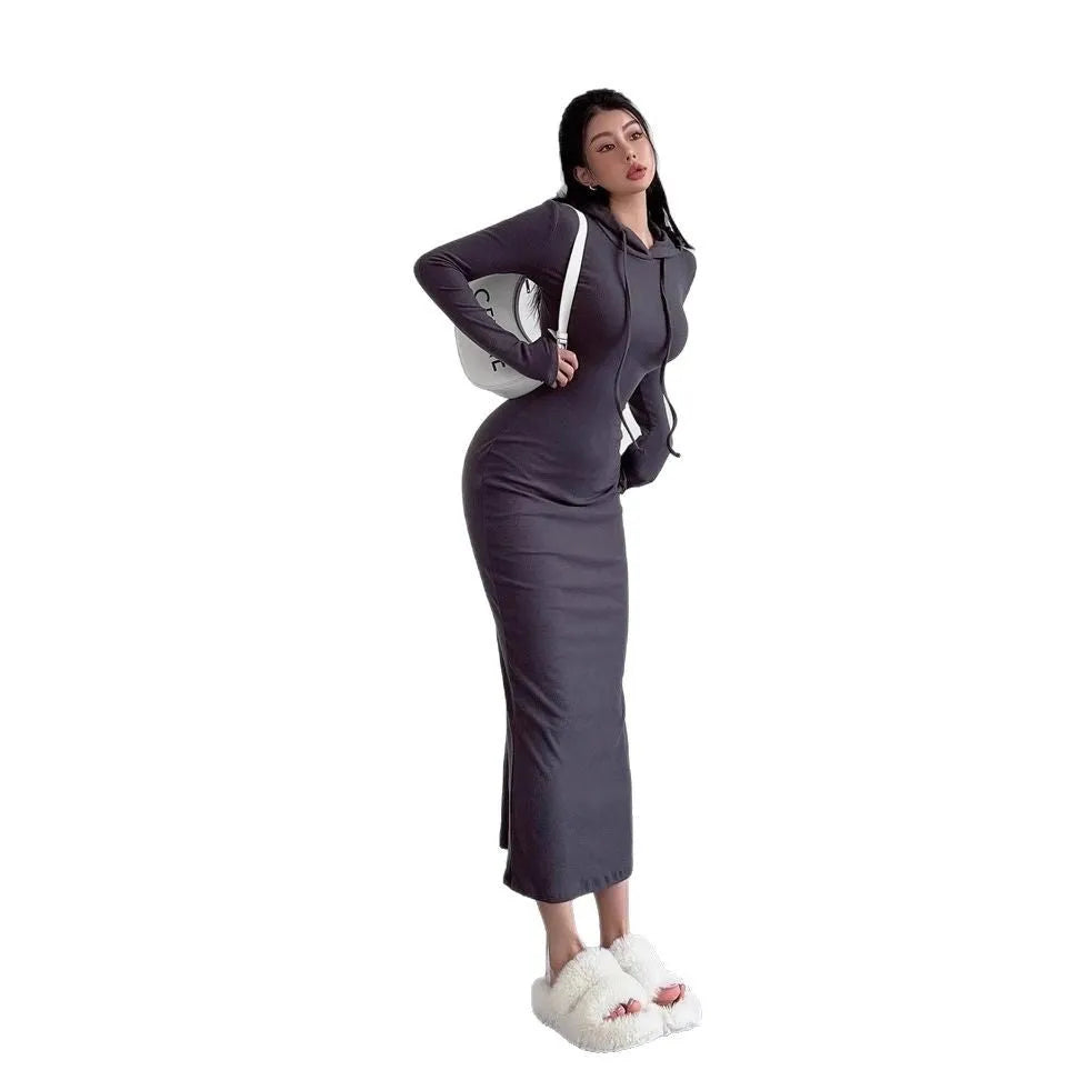 A woman wearing a light grey hooded sheath dress with long sleeves, showcasing the high waist and over-the-knee length.