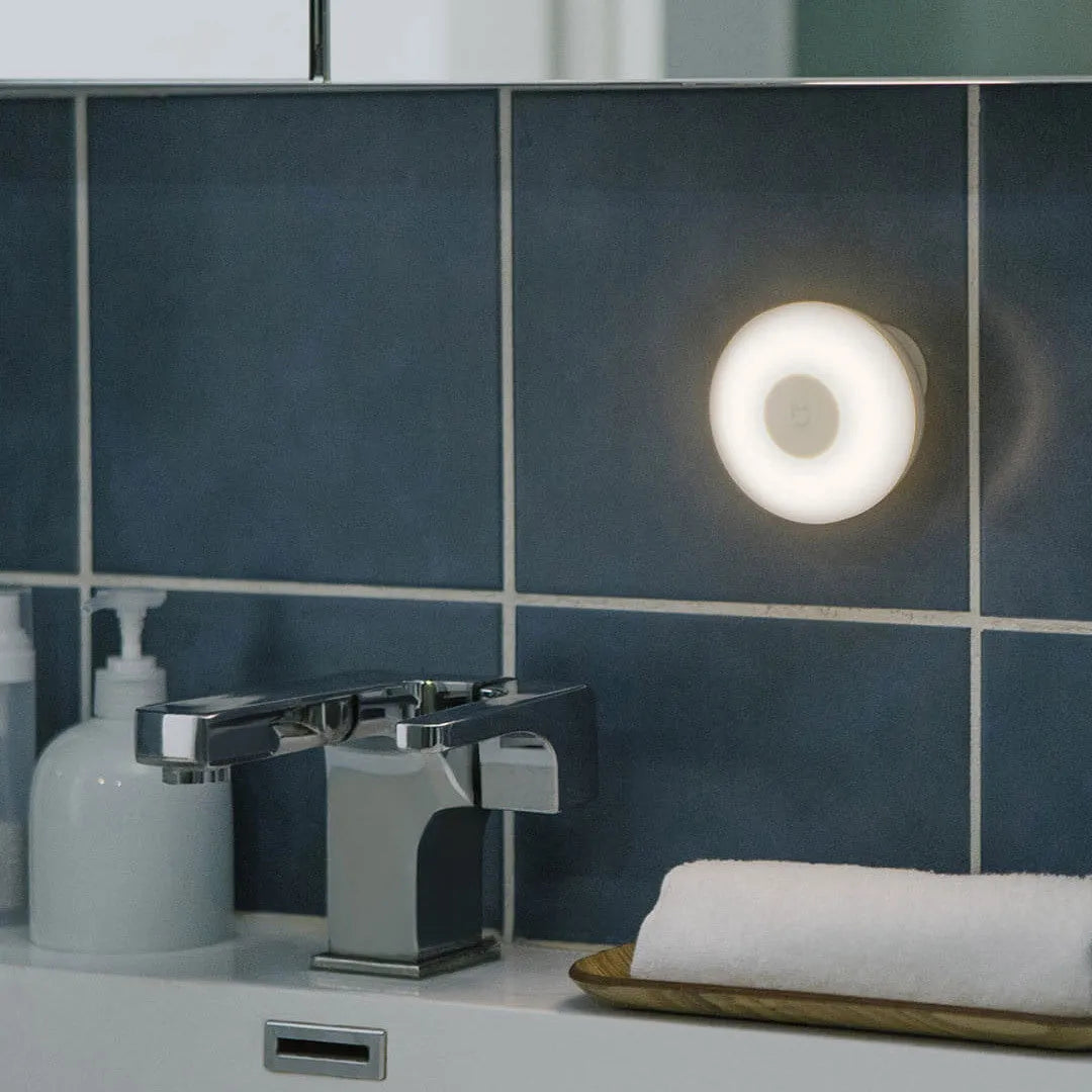 White modern bedside table lamp with human body induction and Bluetooth on a nightstand.