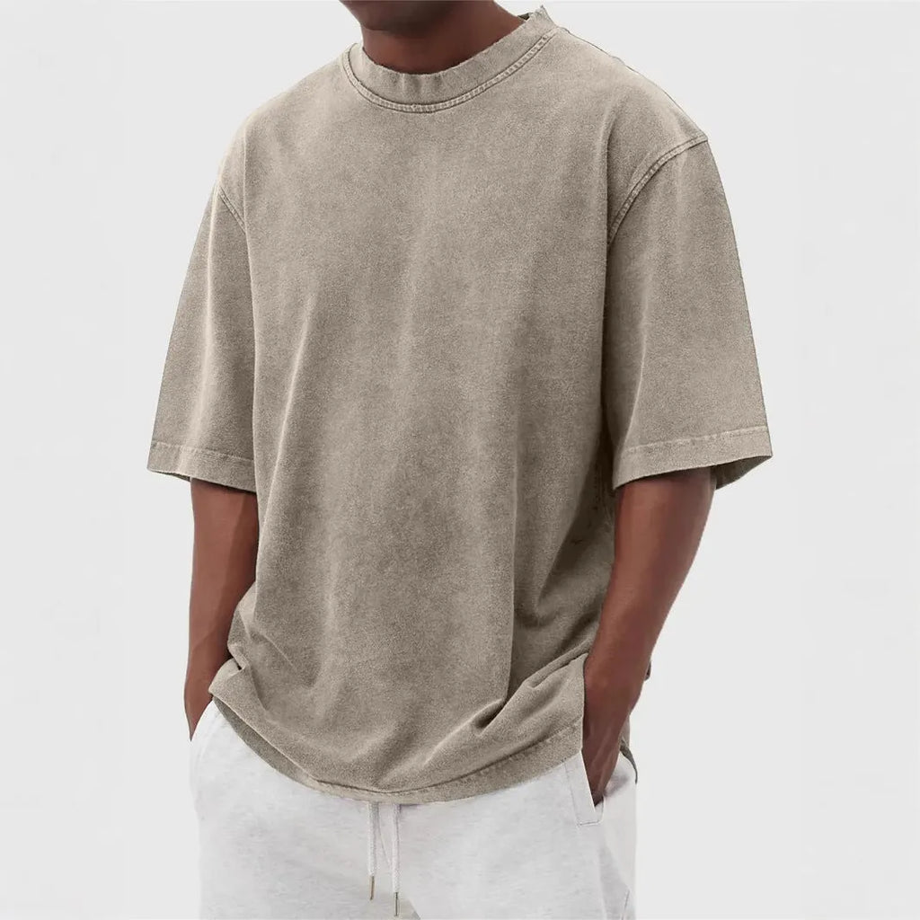 Man wearing a loose-fit, stone-washed grey t-shirt with a distressed solid colour finish and half sleeves.