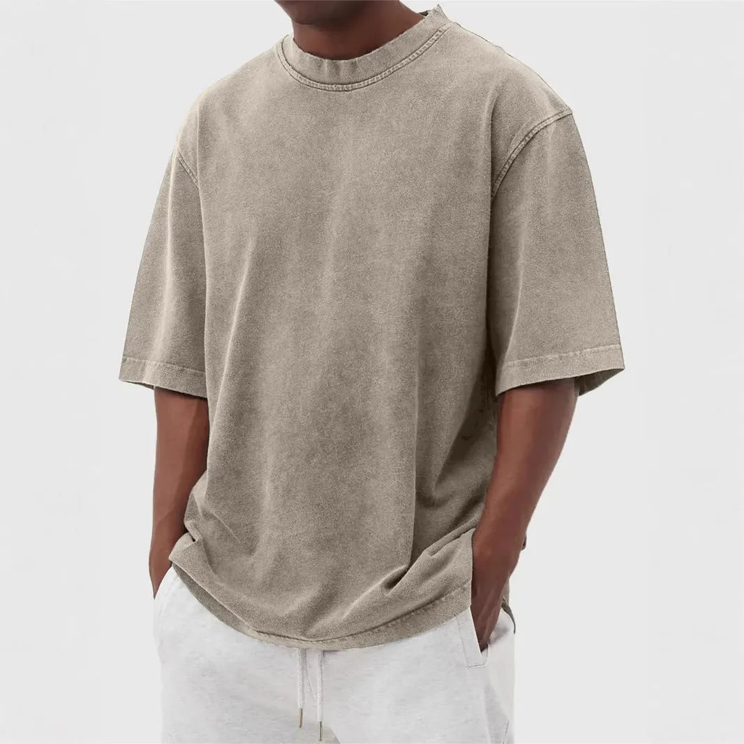 Man wearing a loose-fit, stone-washed grey t-shirt with a distressed solid colour finish and half sleeves.