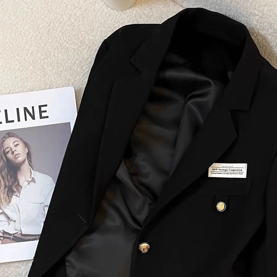 Women's loose fit short suit coat in black polyester fabric with pockets.