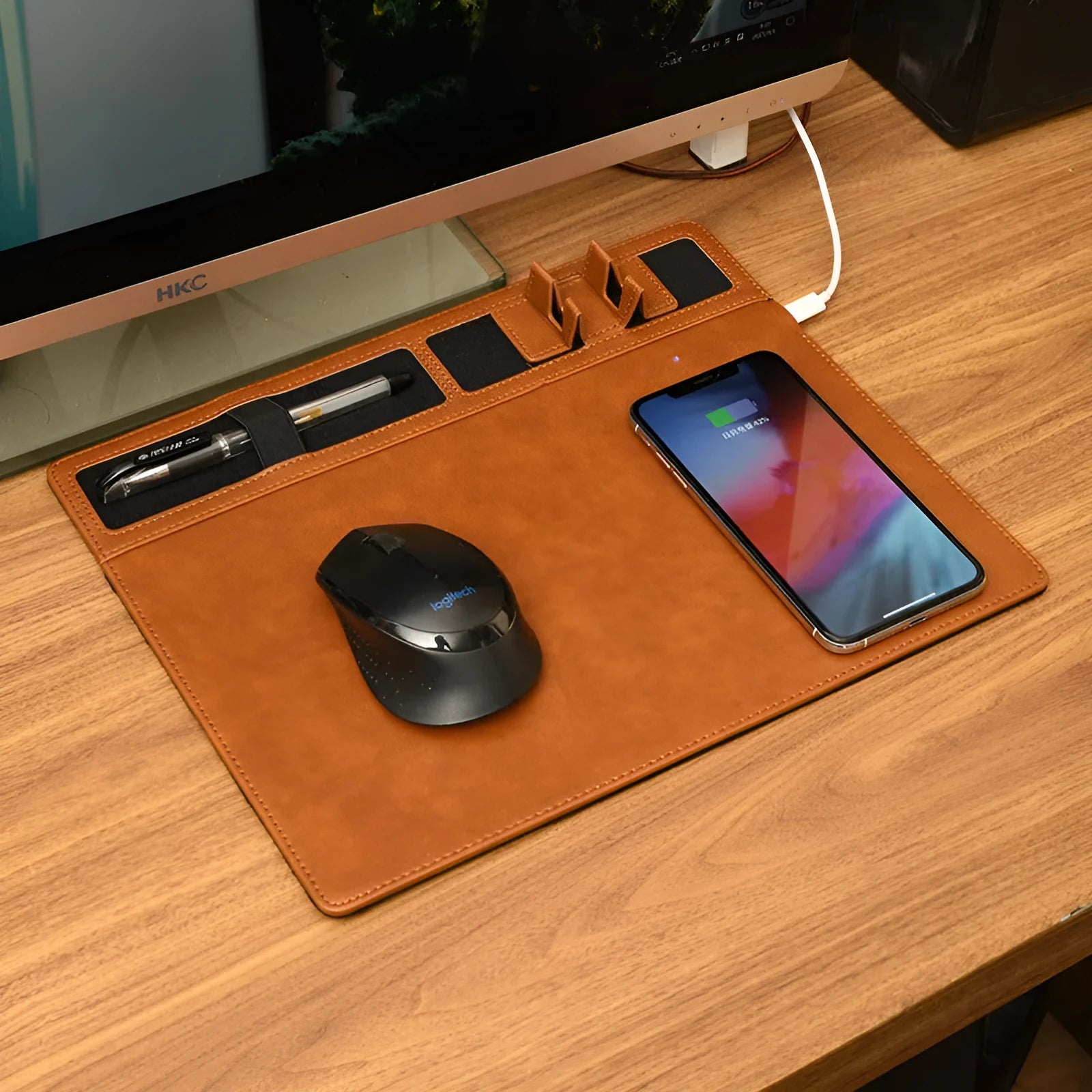 Pink PU leather wireless charging mouse pad with phone holder on a desk, showing USB cable.