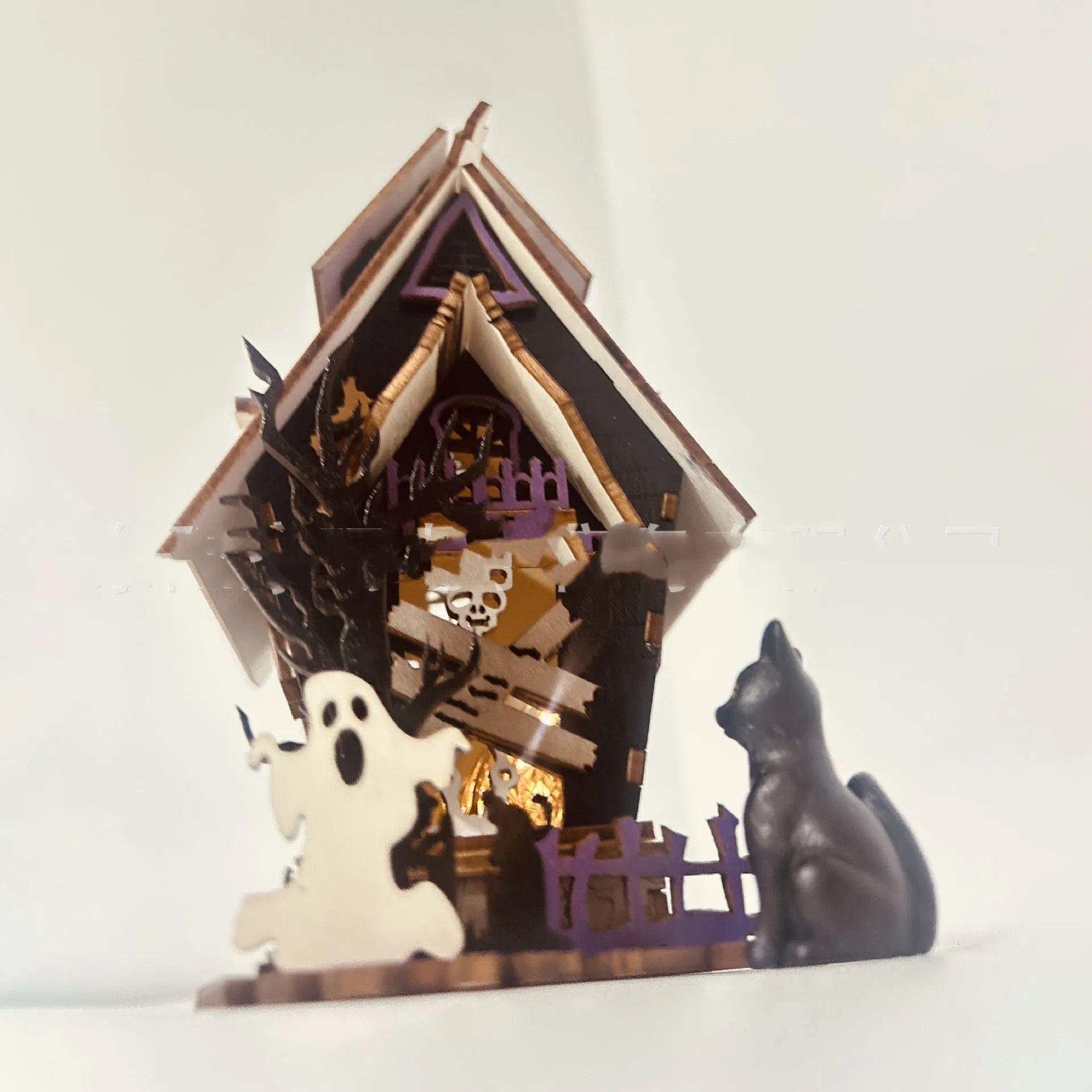 Wooden glowing haunted house Halloween table decoration on a dark surface