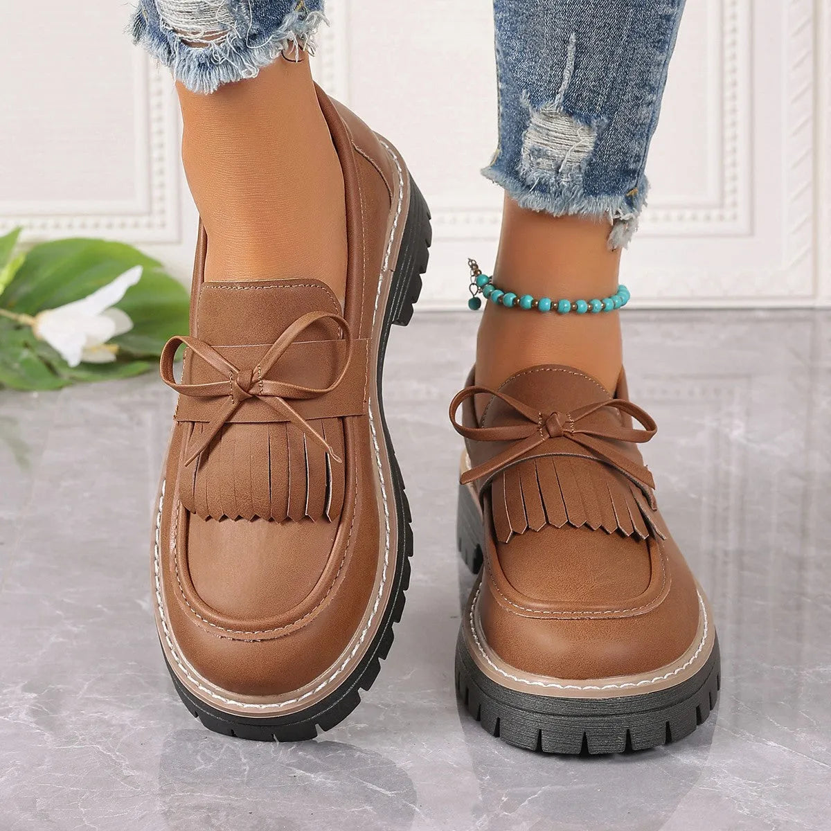 Black plus size women's loafers with a tassel and bowknot decoration on the low-cut upper.
