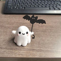 Mini ghost walking dog Halloween statue holding a bat, resin figurine on white background.