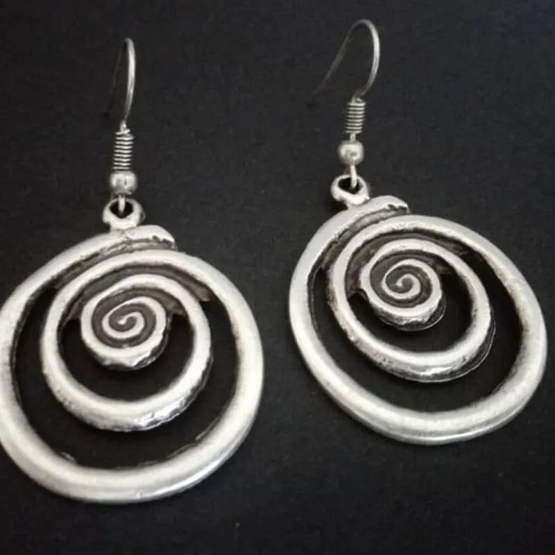 Silver geometric spiral earrings with distressed finish on white background