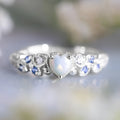 White alloy women's ring with a detailed peach heart and opal flower design.