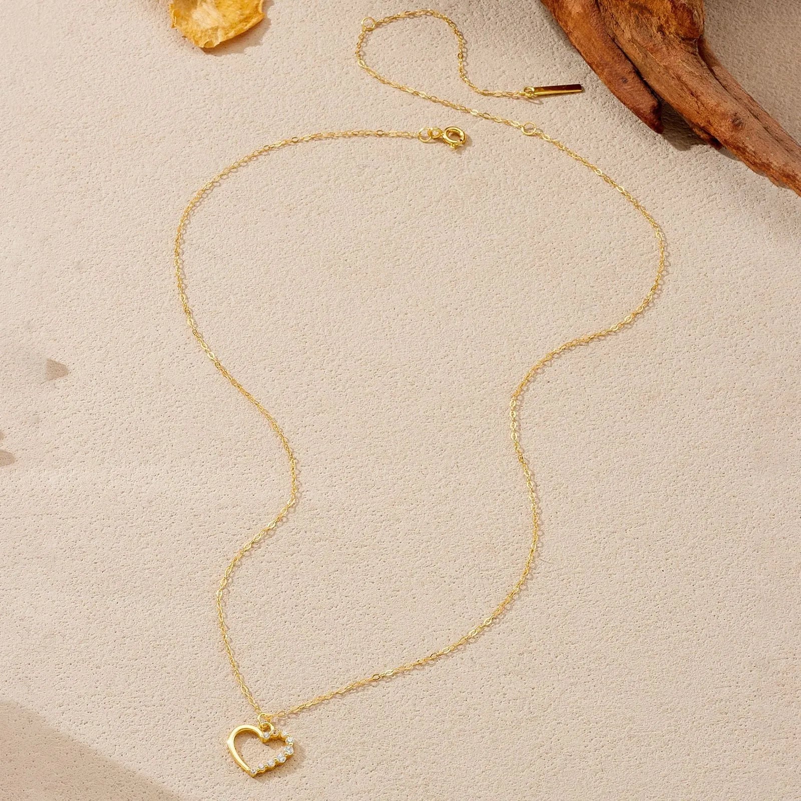 Sterling silver hollow heart and circle pendant necklace on a regular chain, shown in a gold tone finish.