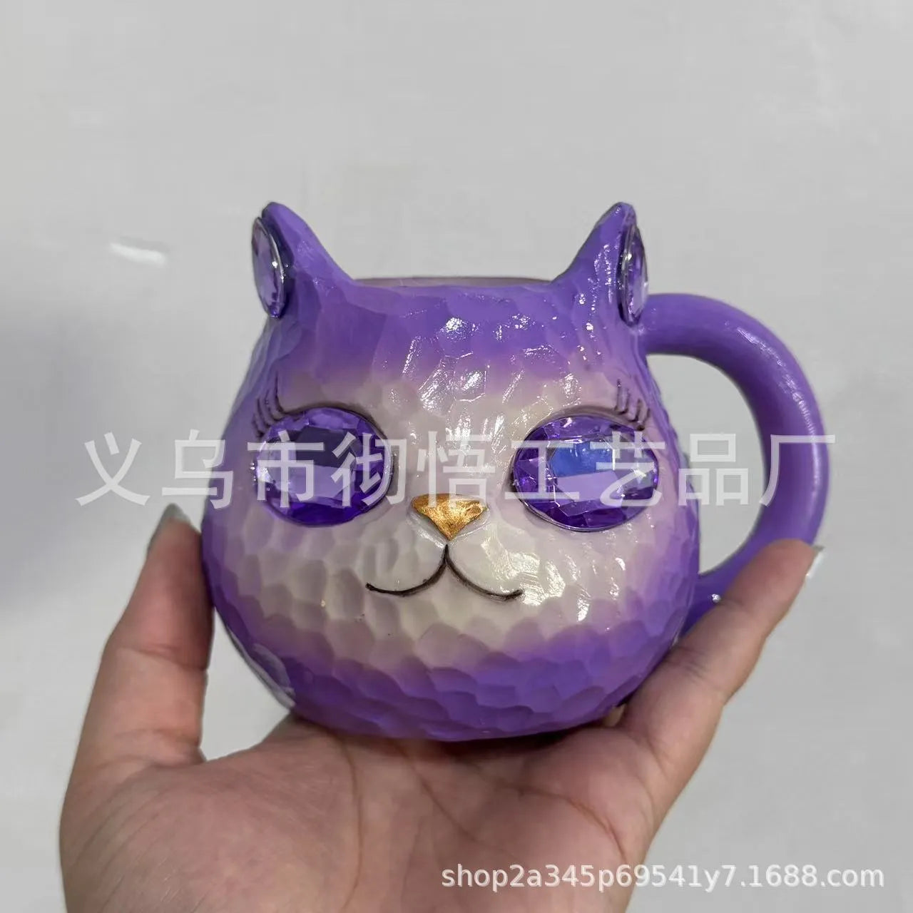 Colourful cat-shaped resin craft ornament in purple, green, blue, or pink on a desk.
