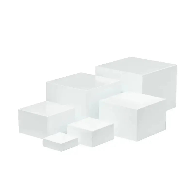 Set of six white plastic cube dessert stands in heights from 3cm to 8cm on a table.