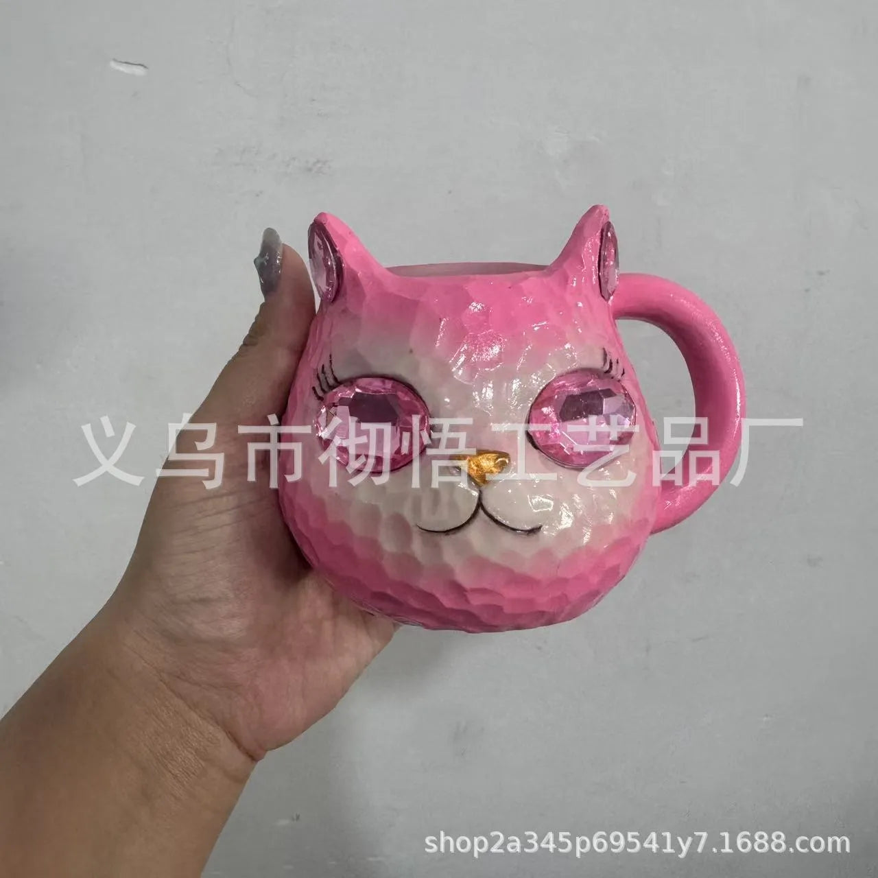 Colourful cat-shaped resin craft ornament in purple, green, blue, or pink on a desk.