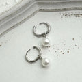 A pair of women's geometric round pearl drop earrings with a titanium steel finish and alloy construction.