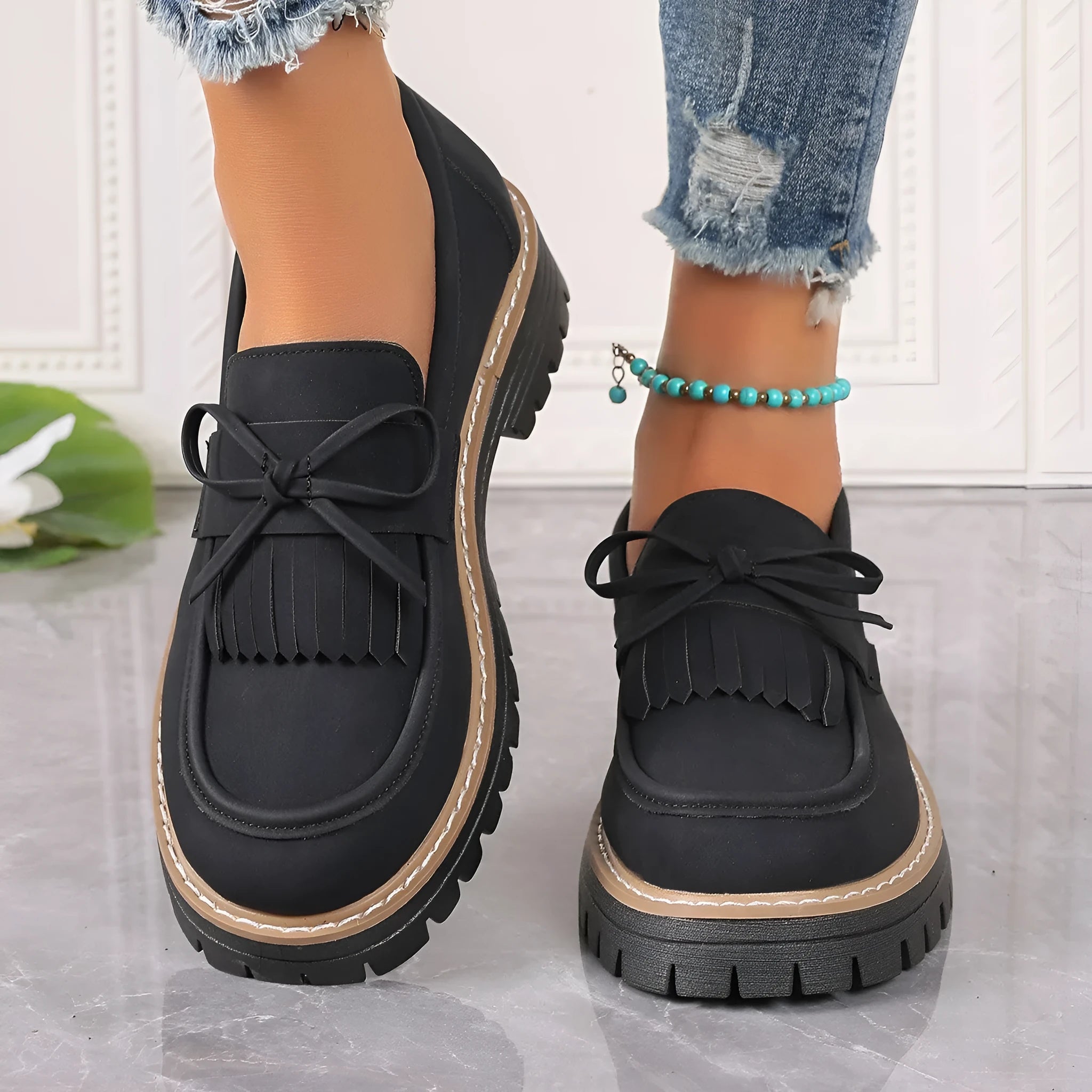 Black plus size women's loafers with a tassel and bowknot decoration on the low-cut upper.