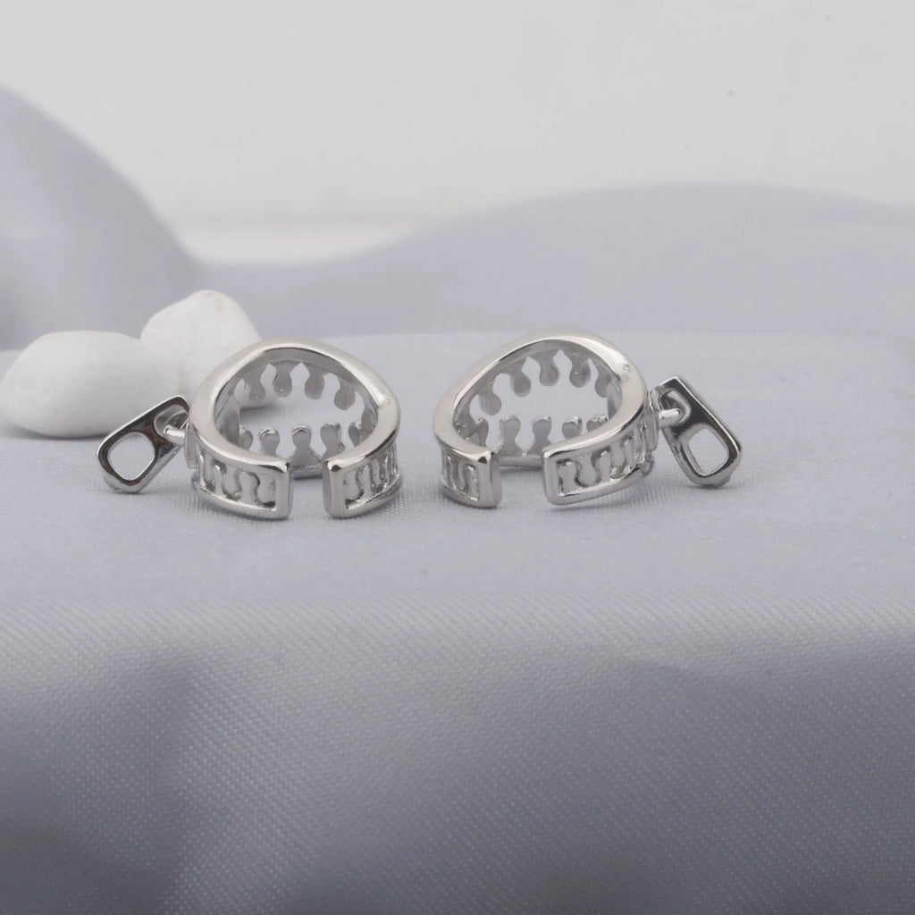A pair of geometric copper clip-on earrings with a zip pull detail, in colour ES862, showing the bone clip fastening.
