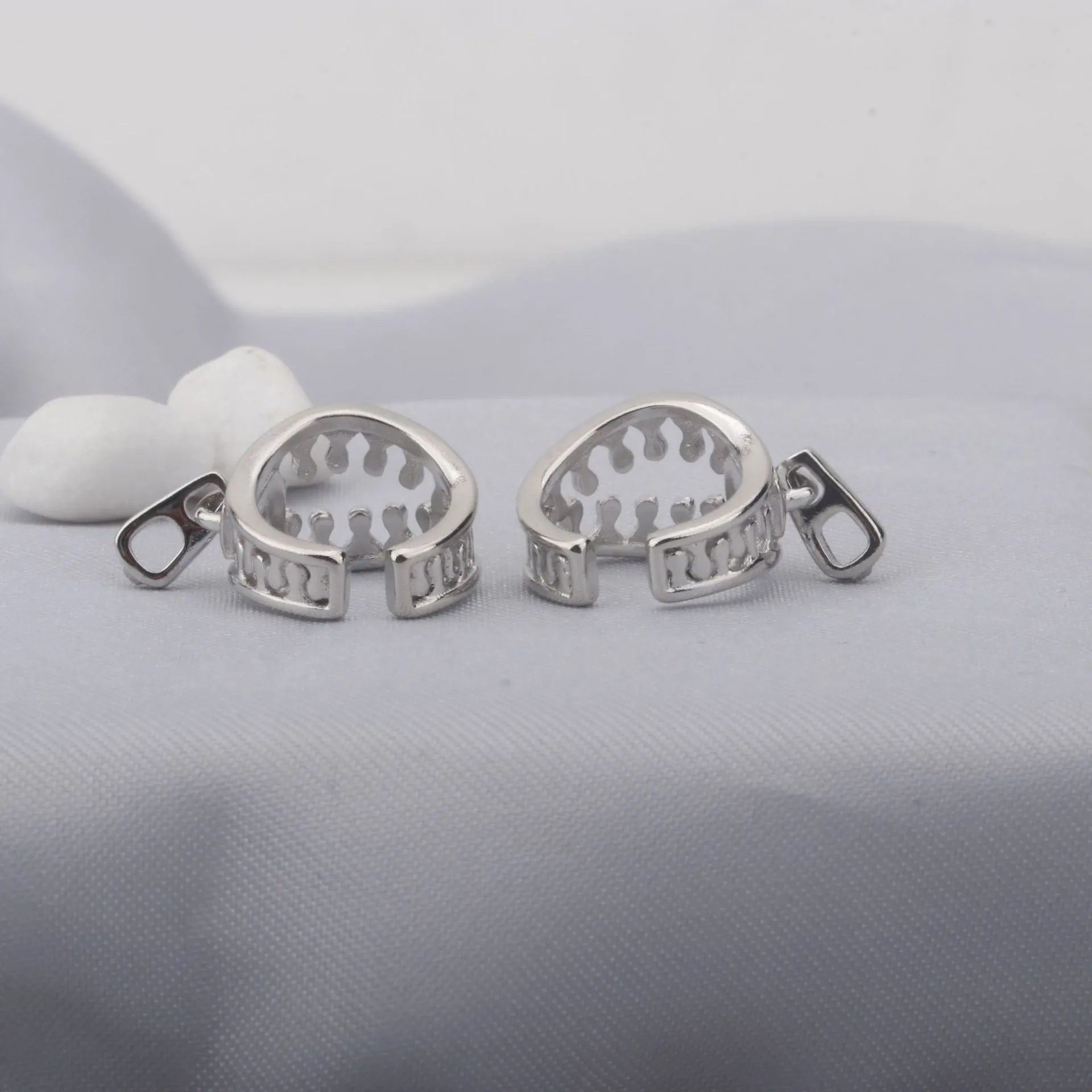 A pair of geometric copper clip-on earrings with a zip pull detail, in colour ES862, showing the bone clip fastening.