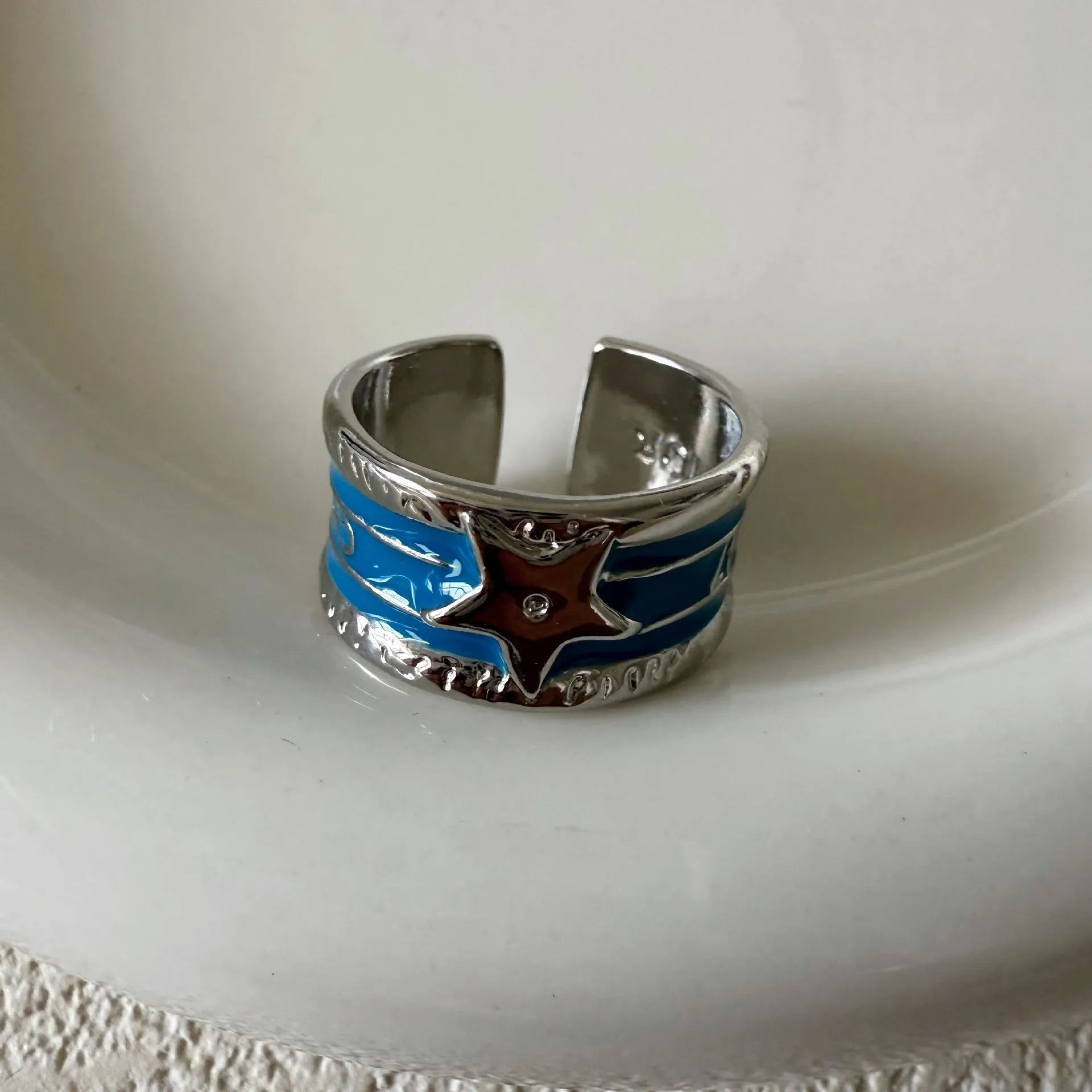Adjustable copper drop oil ring with a distressed XINGX design in geometric shape.