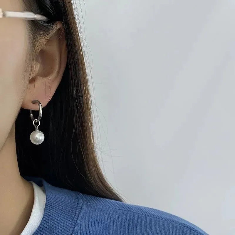 A pair of women's geometric round pearl drop earrings with a titanium steel finish and alloy construction.