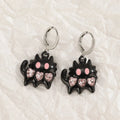 Women's alloy drop earrings featuring cross, heart, and cat charms in white, black, and antique silver finishes.