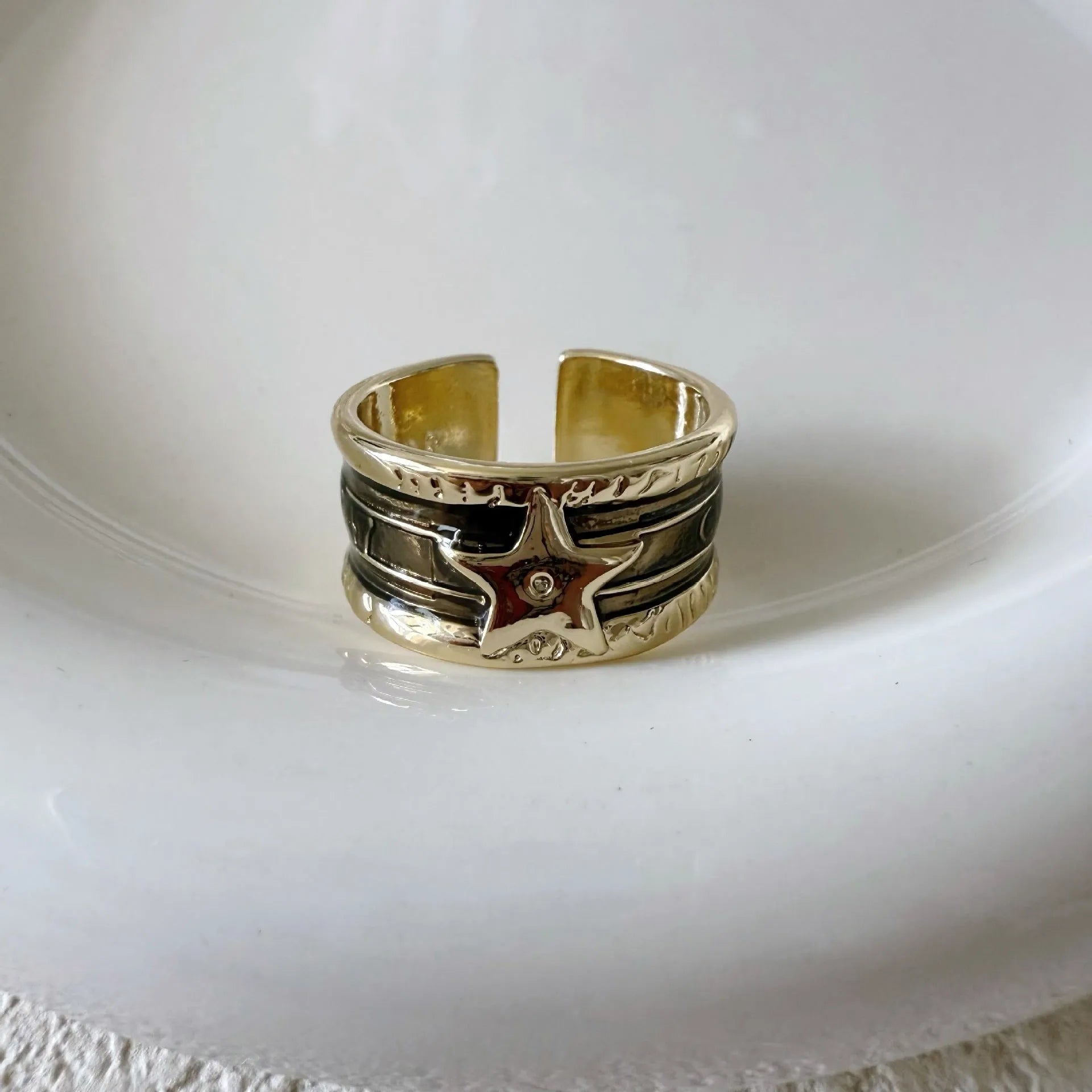 Adjustable copper drop oil ring with a distressed XINGX design in geometric shape.