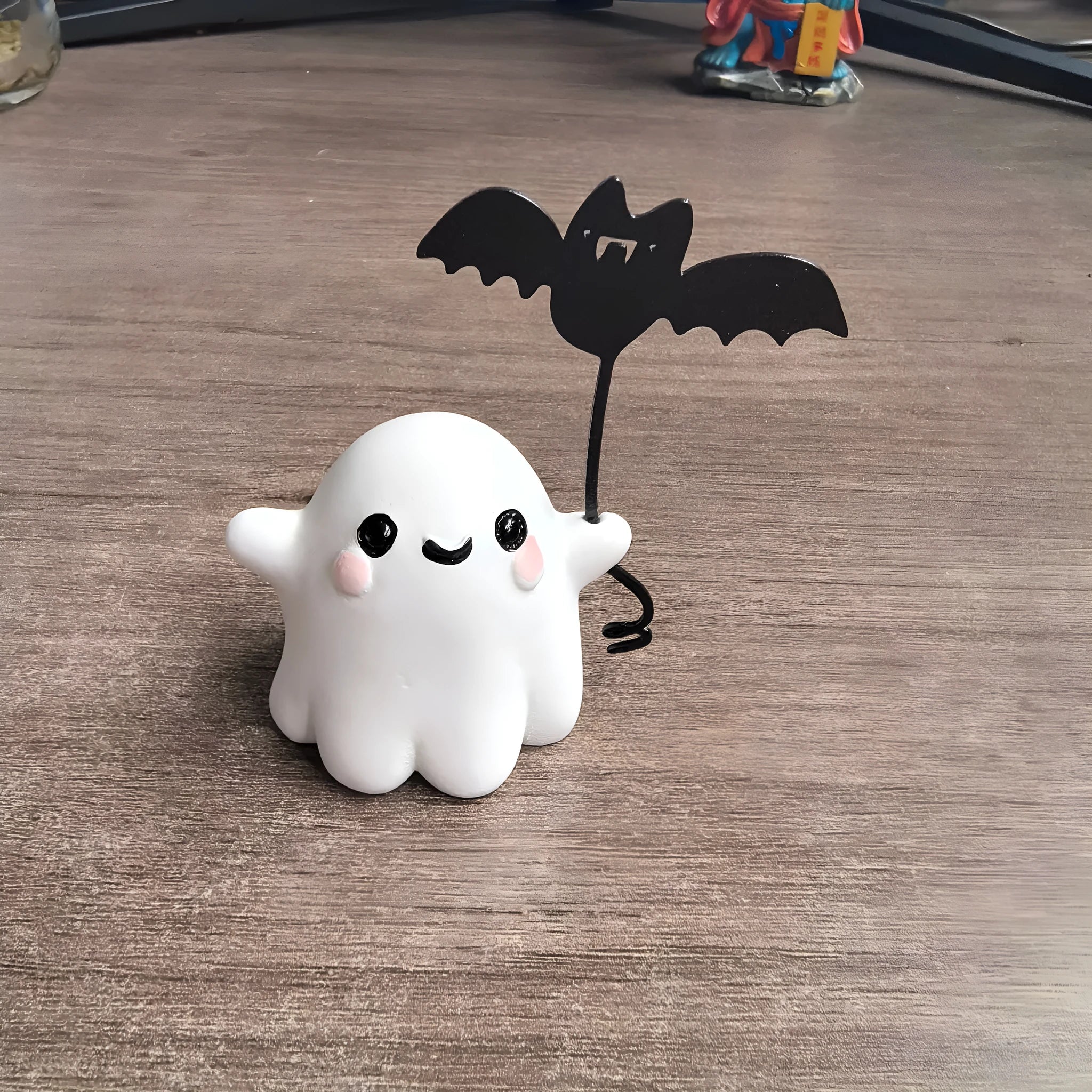 Mini ghost walking dog Halloween statue holding a bat, resin figurine on white background.